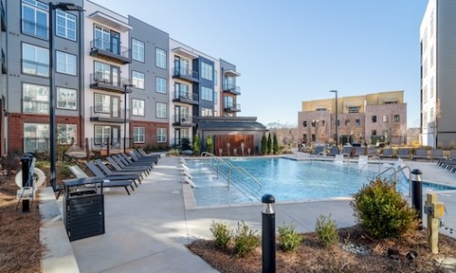 Large sparkling blue pool with a large deck and lounge chairs 